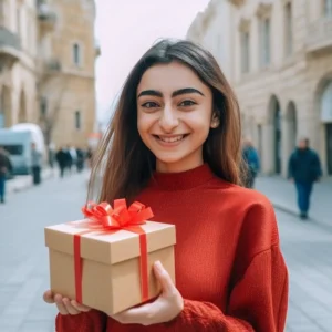 AliExpress Azerbaijan: A young and happy Azerbaijani woman stands in the center of Baku and holds a gift box in her hands.